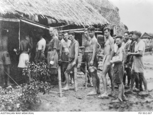 A group of people standing in front of a hut.