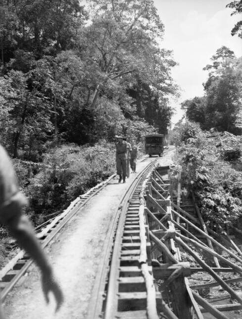 Prisoners of war walking along a railway track over water.
