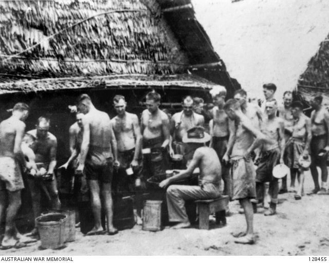 A group of prisoner of wars in a line up for a mess parade.