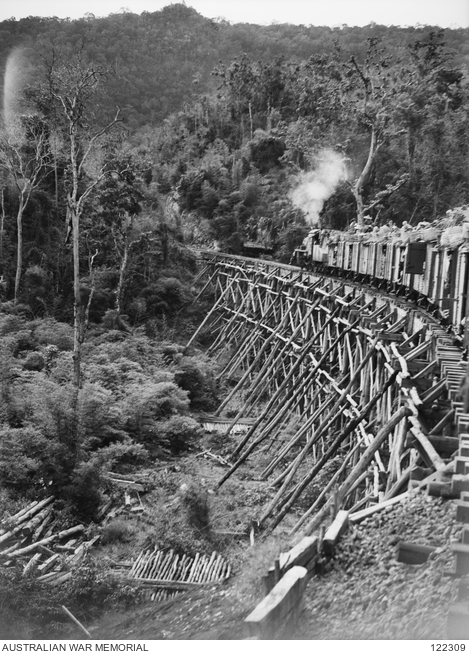 A train on a curved trestle railway line bridge.
