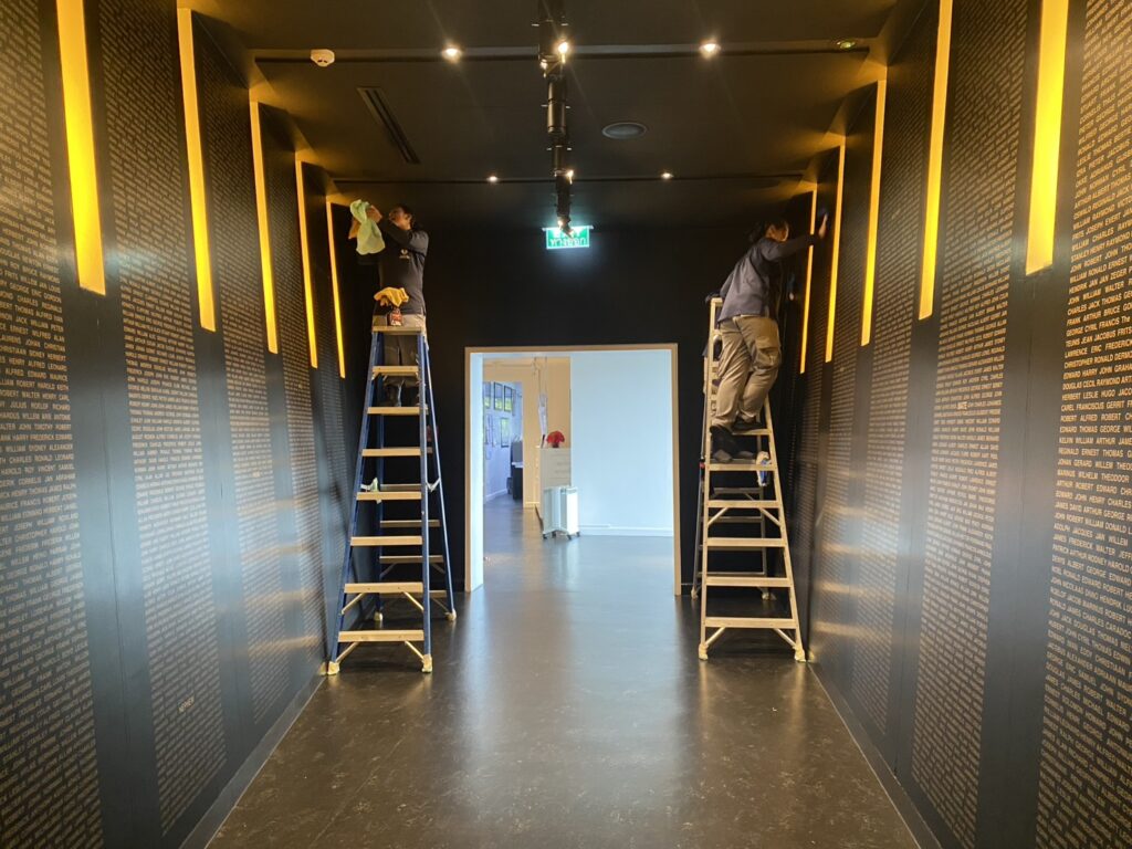 Staff on ladders cleaning the upper wall of the gallery
